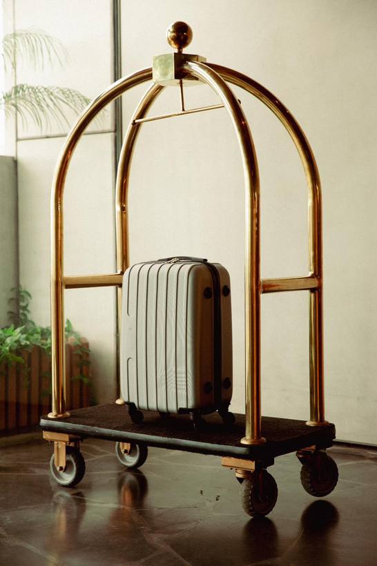 A suitcase on a brass luggage cart in a hotel entrance
