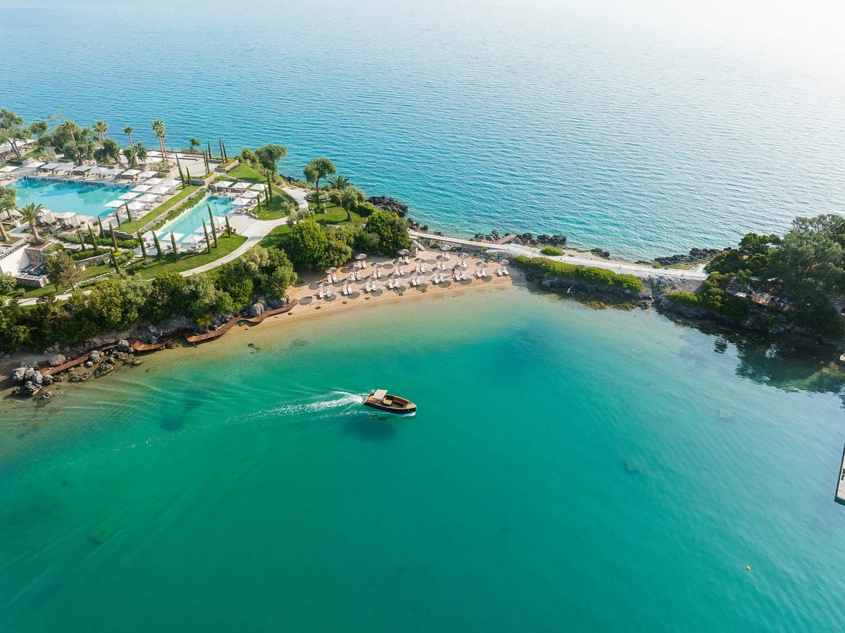Sandy cove, pools and a launch on turquoise water, Grecotel Corfu Imperial